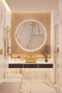 Bathroom with marble walls, round backlit mirror, golden sink, and decorative accents.